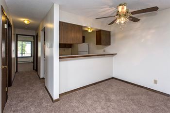 a living room with a ceiling fan and a kitchen in the background